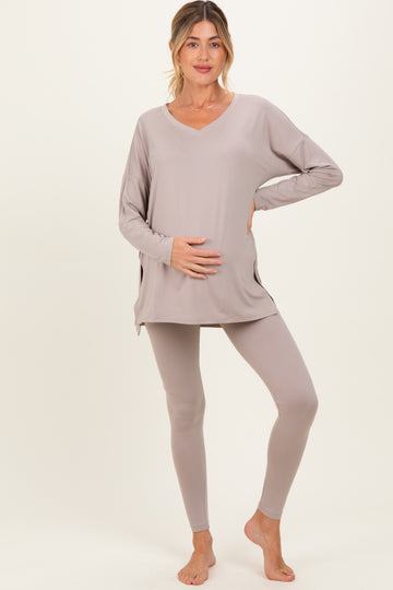 woman wearing a taupe maternity long sleeve top and matching leggings, holding her baby bump