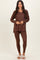 woman wearing a brown long sleeve top with a v-neck and brown leggings, styled with fluffy slippers