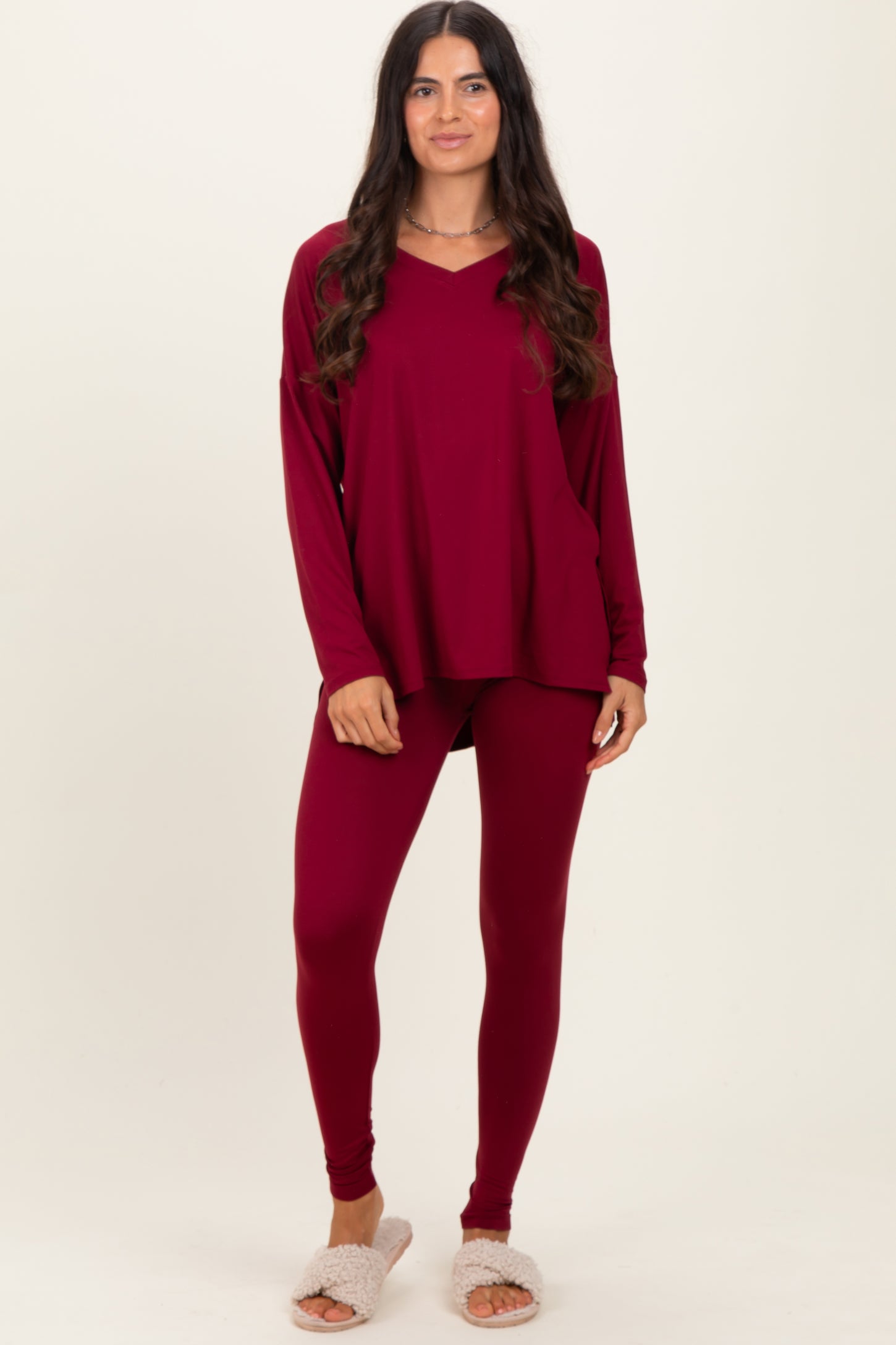 woman wearing a burgundy long sleeve top and matching leggings with cozy slippers on her feet