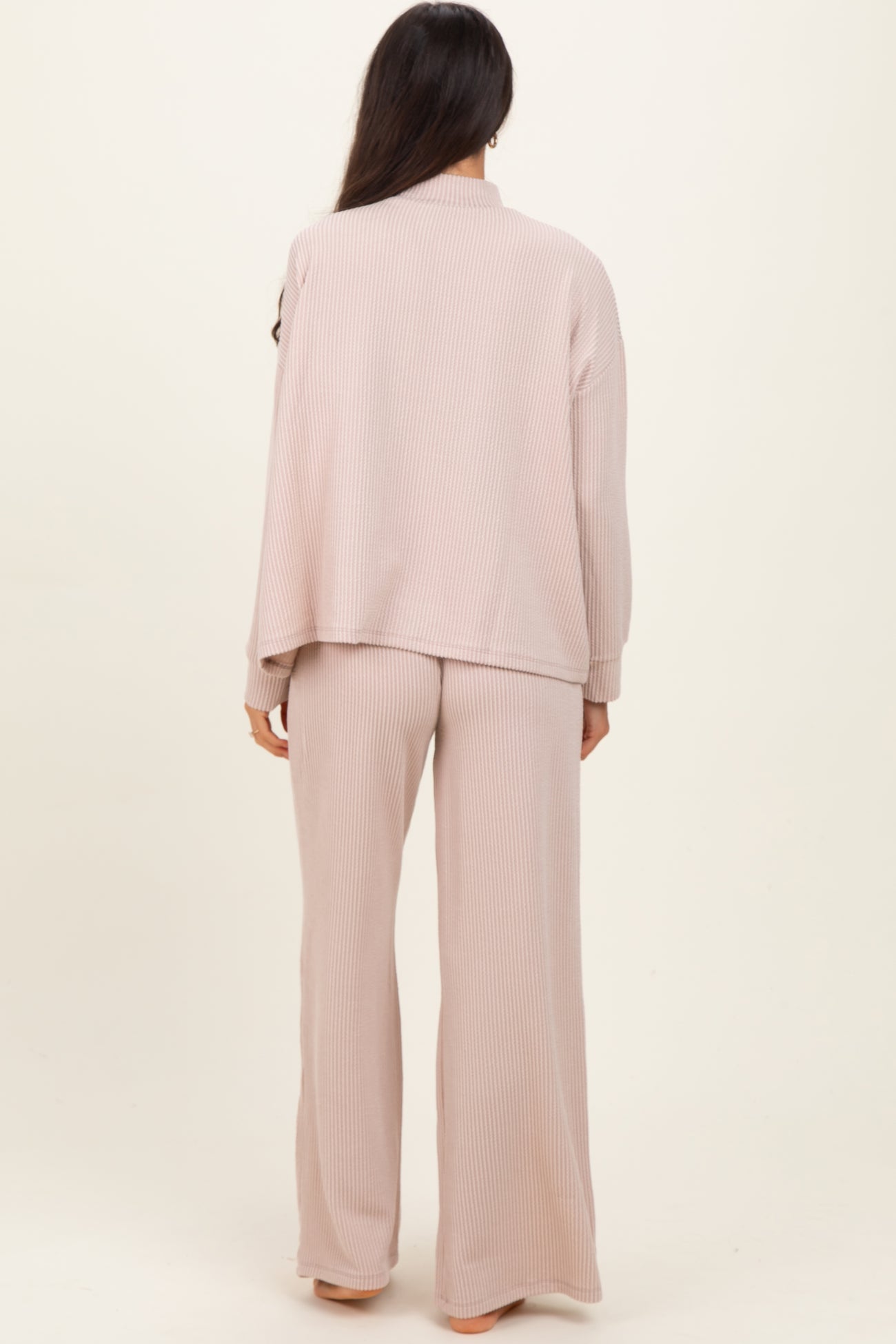 woman wearing a light pink ribbed loungewear set with a loose-fitting top and matching wide-leg pants, viewed from the back