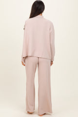 woman wearing a light pink ribbed loungewear set with a loose-fitting top and matching wide-leg pants, viewed from the back