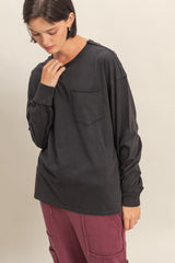 woman wearing a black long sleeve top with a chest pocket and styled with relaxed fit maroon trousers