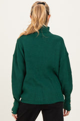 maternity wear in dark green ribbed sweater with a high neck and oversized fit, features button details on sleeves