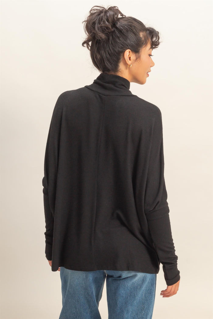 woman wearing a black turtleneck sweater with a relaxed fit and long sleeves, seen from the back