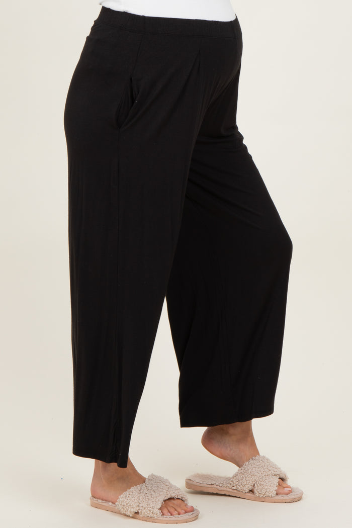 maternity wear black wide-leg pants with side pockets, model wearing soft slippers and a white top
