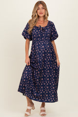 woman wearing a navy blue floral maternity maxi dress with puff sleeves and a tie-front detail