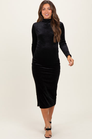 woman wearing a black velvet maternity dress with a high neck and long sleeves, showing her baby bump