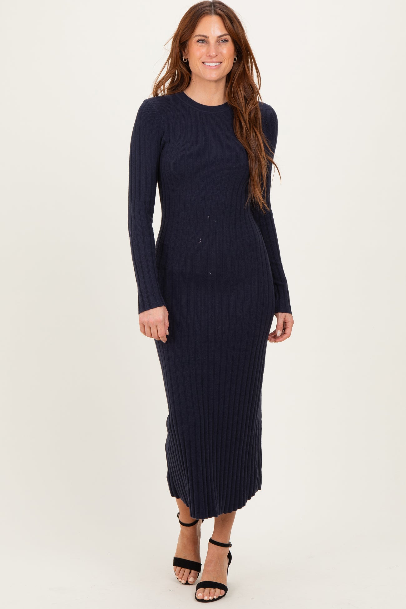 woman wearing a navy blue ribbed long sleeve midi dress and black strappy heels