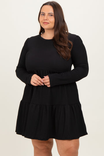 woman wearing a black long sleeve plus size dress with a tiered skirt and ribbed texture