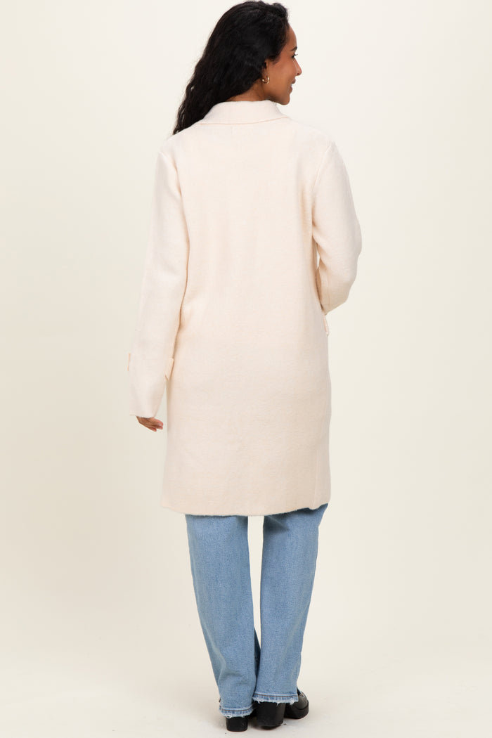 woman wearing a light pink long cardigan with a back view, paired with light blue jeans, maternity wear