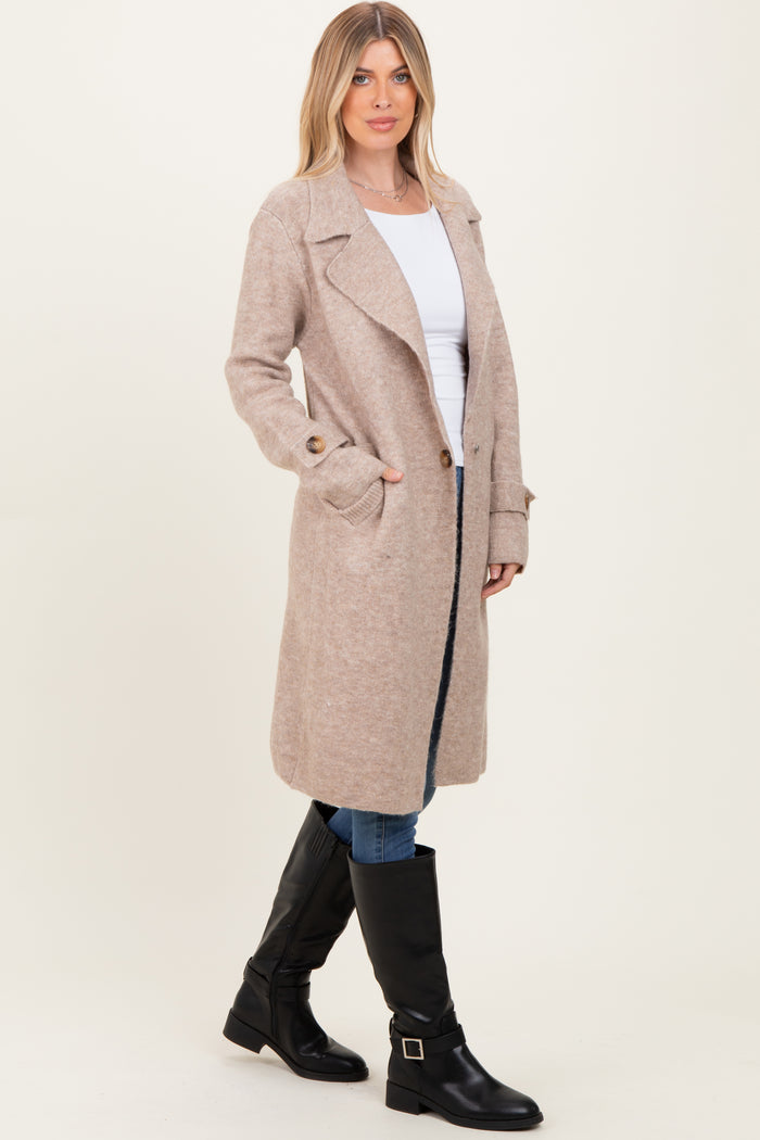 woman wearing a beige long wool blend coat, white top, blue jeans, and black knee-high boots