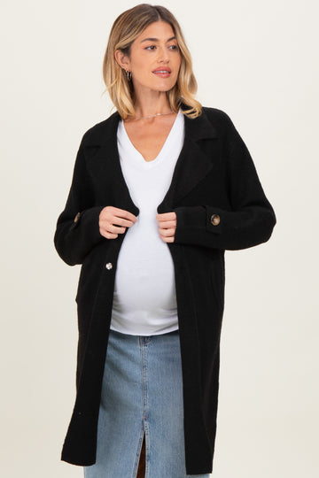 woman wearing a black maternity cardigan over a white top and showing her baby bump, styled with a denim skirt