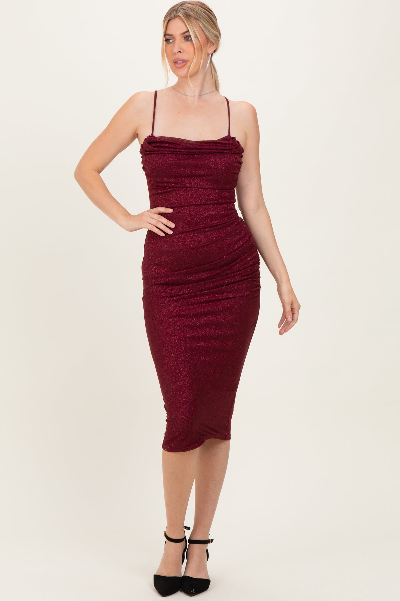 woman wearing a burgundy ruched midi dress with thin straps and a form-fitting silhouette