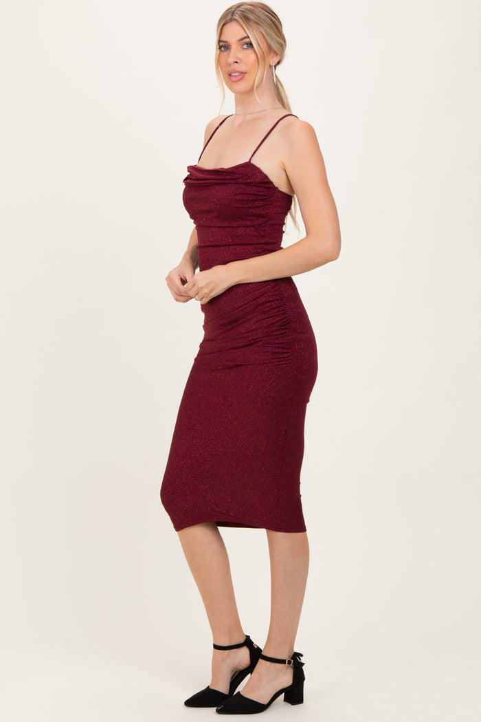 woman wearing a burgundy sparkly midi dress with ruching and thin straps, styled with black ankle-strap heels