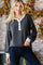 woman wearing a dark grey striped long sleeve top with a white button placket and contrasting cuffs