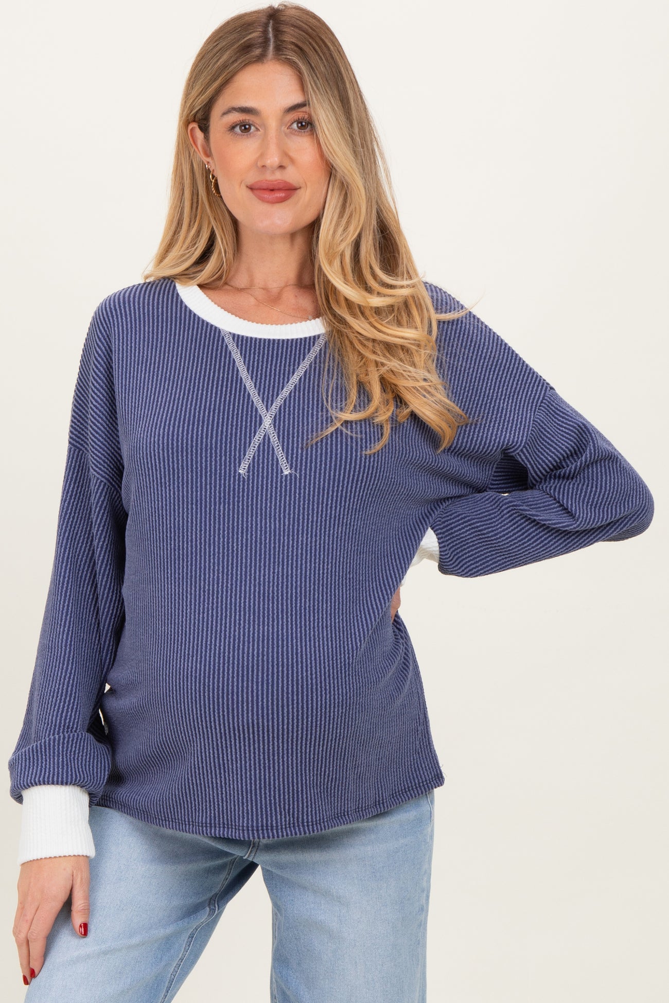 woman wearing a navy blue ribbed maternity sweater with white accents and a visible baby bump