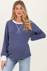 woman wearing a navy blue ribbed maternity sweater with white accents and a visible baby bump