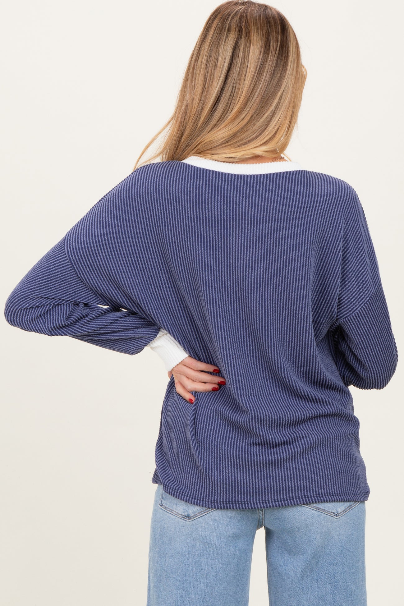 woman wearing a navy blue ribbed maternity sweater with white detailing, viewed from the back