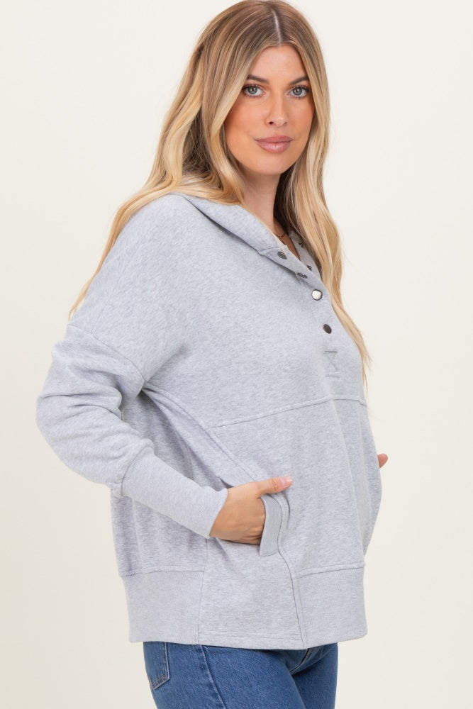 woman wearing a gray oversized hoodie with a button-up neckline and front pockets