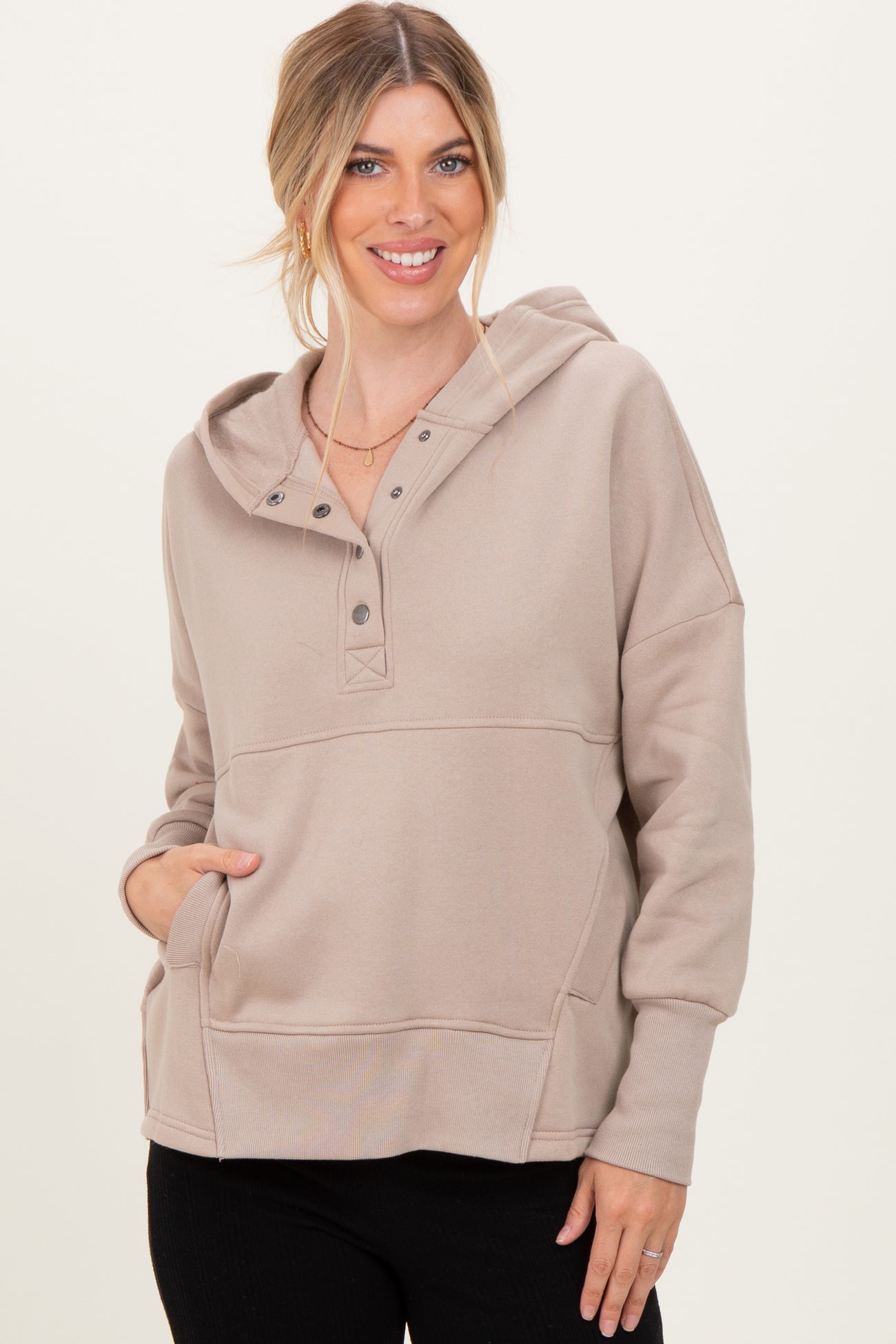 woman wearing a beige hooded sweatshirt with button details and a front pocket