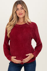 woman wearing a burgundy maternity sweater with ribbed texture and long sleeves, holding her baby bump