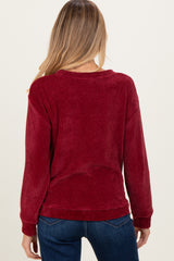 woman wearing a burgundy knit maternity sweater, facing away, showing loose fit and long sleeves