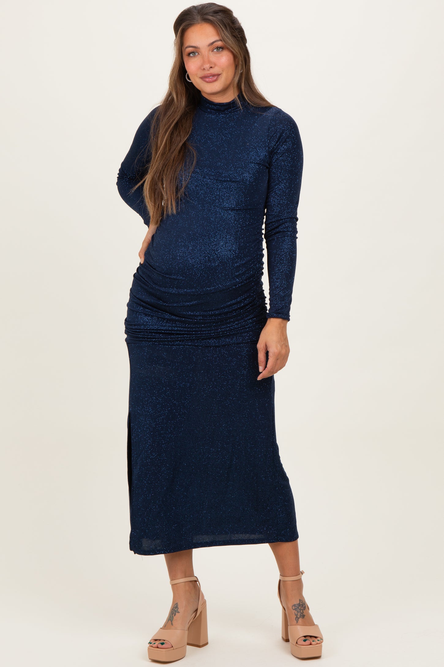 woman wearing a navy blue long sleeve maternity dress with ruching and a side slit, showing her baby bump