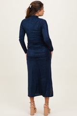 woman wearing a navy blue sparkly long sleeve maternity dress with ruched details and a mid-length cut
