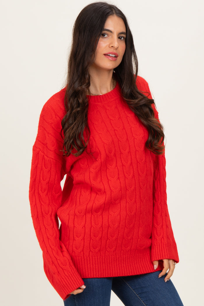 woman wearing a red cable knit sweater with long sleeves and ribbed hem paired with blue jeans