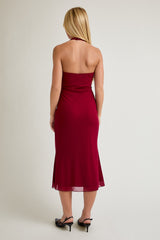 woman wearing a burgundy halter neck midi dress, showing a fitted silhouette from the back