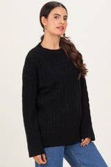 woman wearing a black cable knit sweater with a relaxed fit and long sleeves paired with blue jeans