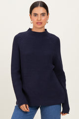 woman wearing a dark navy ribbed knit sweater with a high neckline and relaxed fit, paired with blue jeans