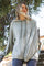 woman wearing a light gray oversized hoodie with a front kangaroo pocket and drawstring hood