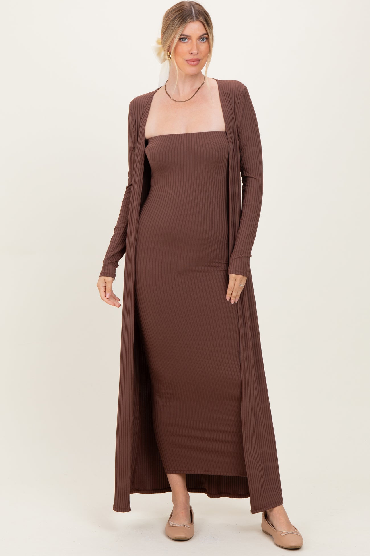 woman wearing a brown ribbed maxi dress with a long cardigan, styled with tan flats and hair in a loose updo