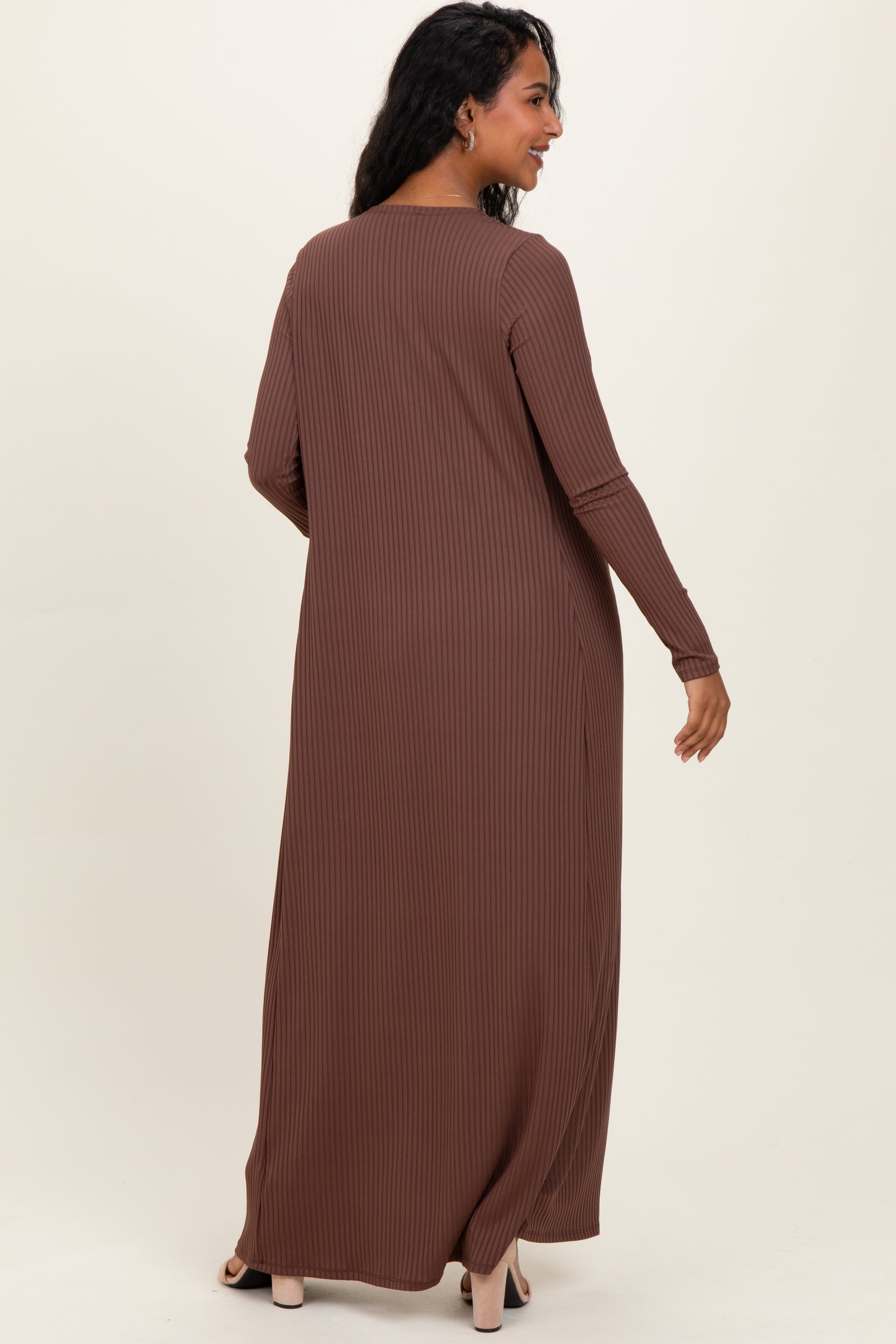 woman wearing a long brown ribbed maternity dress, featuring long sleeves and a relaxed fit