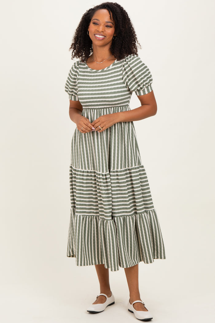 woman wearing a green and white striped midi dress with puff sleeves and a tiered skirt, smiling at the camera