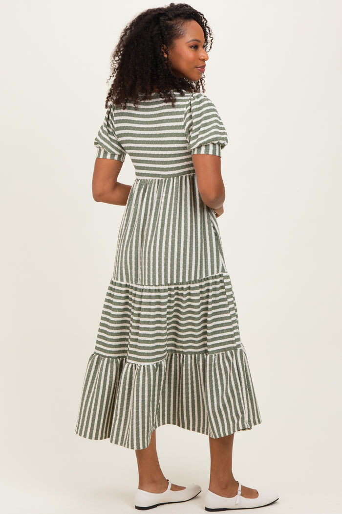woman wearing a green and white striped midi dress with tiered ruffles and short sleeves, viewed from the back
