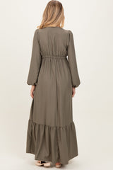 woman wearing a long olive green maternity dress with puffed sleeves and a tiered hem, view from the back