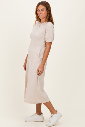 woman wearing a beige midi dress with short puff sleeves and a fitted waist, paired with white sneakers