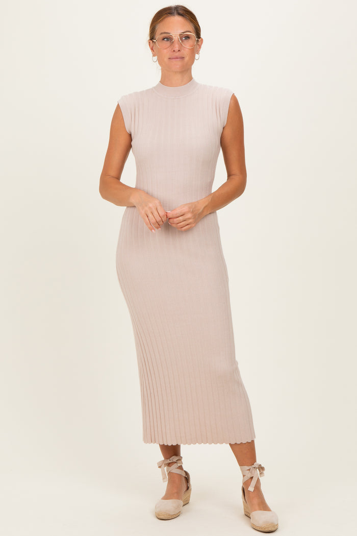 woman wearing a light pink ribbed midi dress with a high neck and cap sleeves, standing and smiling
