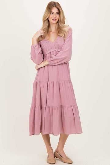 woman wearing a pink tiered midi dress with a smocked bodice and long sleeves