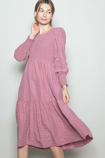 woman wearing a dusty pink long sleeve tiered maxi dress with smocked bodice and puff sleeves