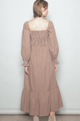 woman wearing a brown checkered long sleeve maxi dress with a smocked back and ruffled hem