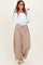 woman wearing a white long sleeve top and taupe wide-leg pants with drawstring waist