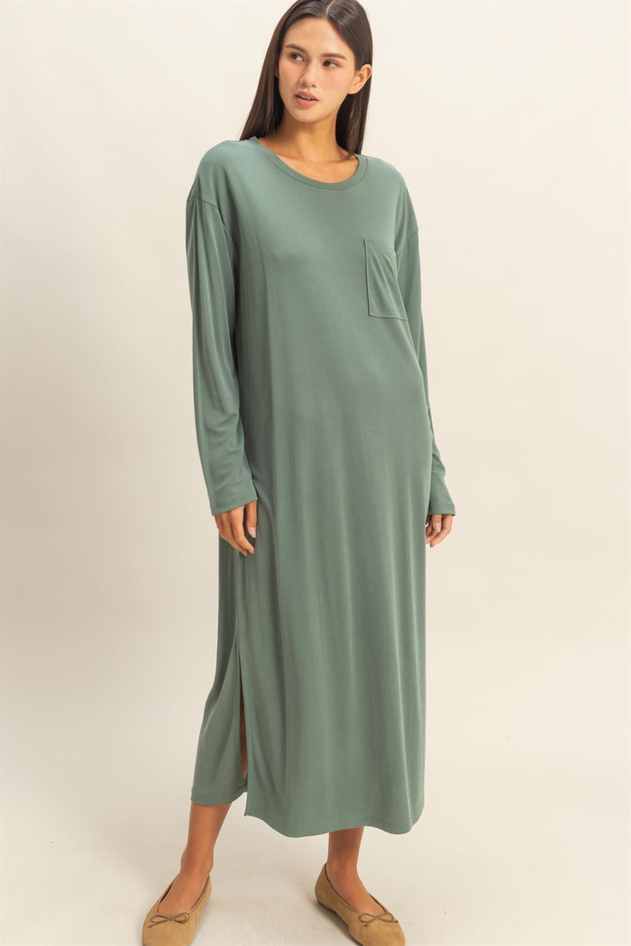 woman wearing a long sage green maxi dress with long sleeves and a side slit detail
