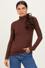 woman wearing a brown long sleeve turtleneck top paired with blue jeans