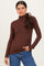 woman wearing a brown long sleeve turtleneck top paired with blue jeans