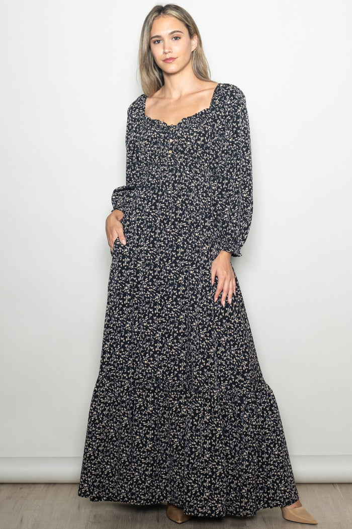 woman wearing a navy blue floral maxi dress with long sleeves and a square neckline, styled with a boho vibe