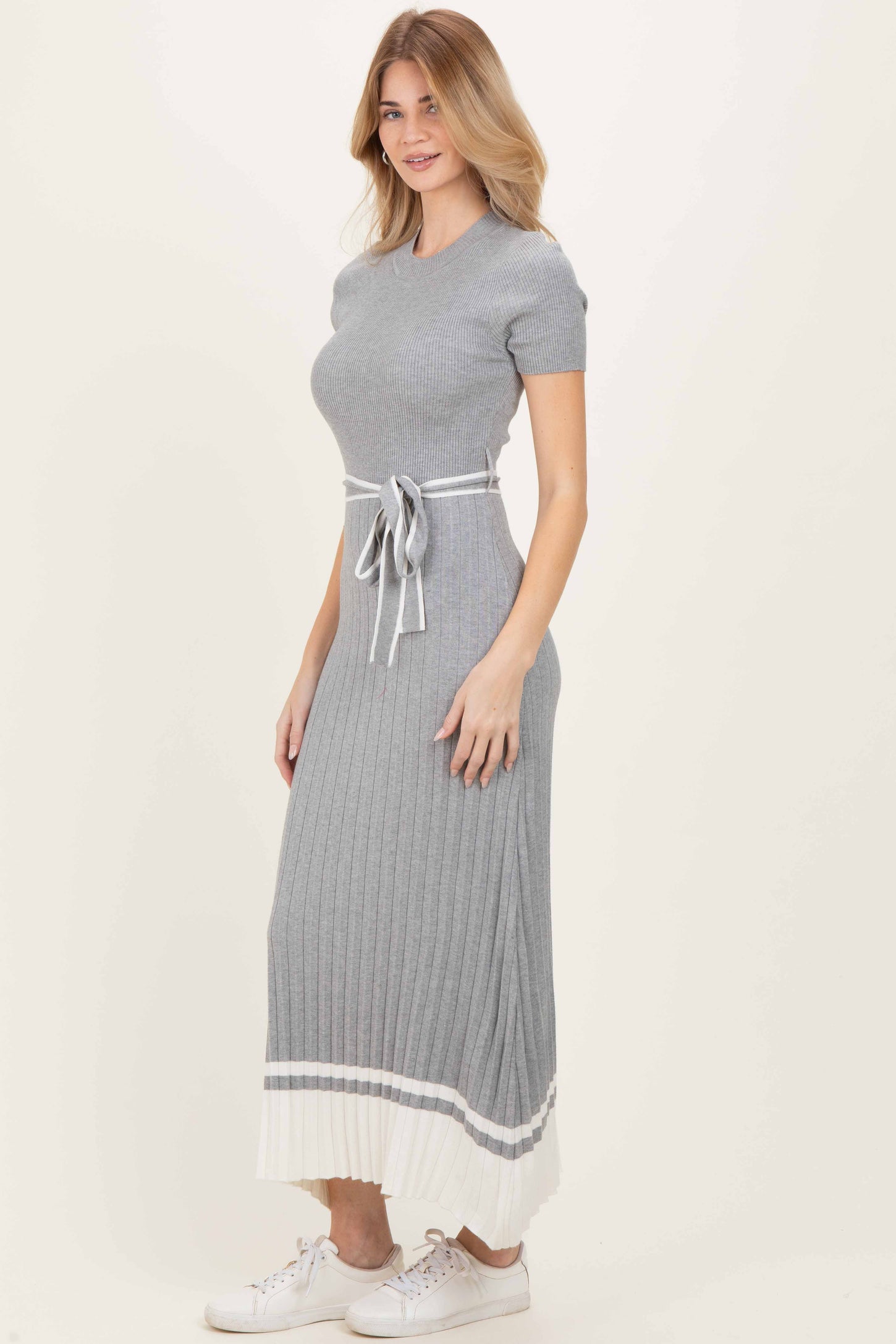 woman wearing a gray ribbed maxi dress with short sleeves and a tie waist detail, styled with white sneakers