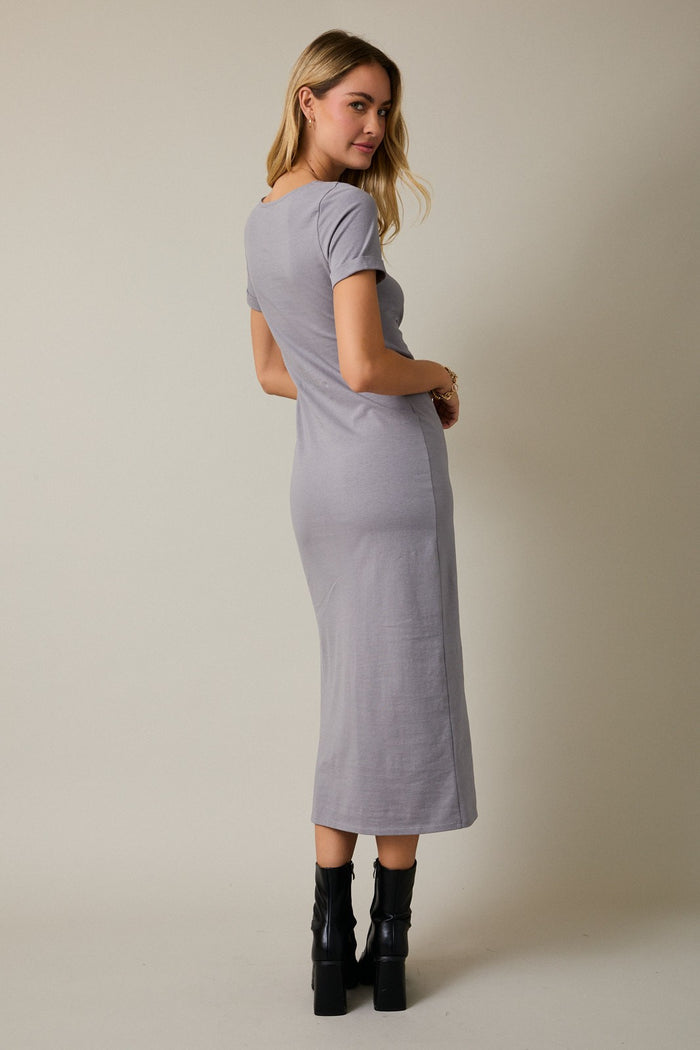 woman wearing a gray short sleeve midi dress and black platform boots, standing with her back to the camera